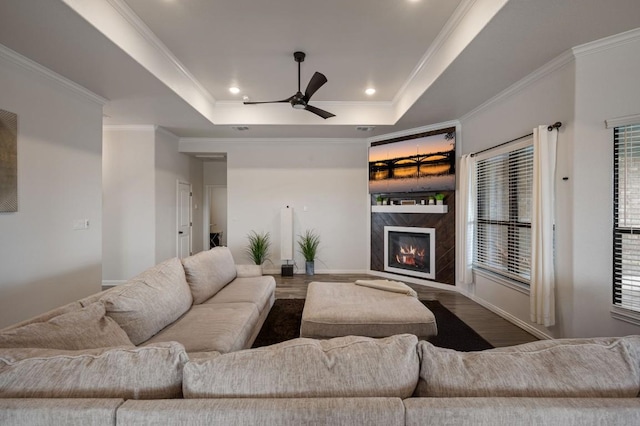 living room featuring recessed lighting, a fireplace, wood finished floors, a ceiling fan, and a raised ceiling