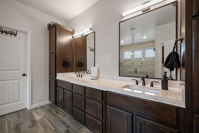 full bath featuring a stall shower, visible vents, a sink, and double vanity