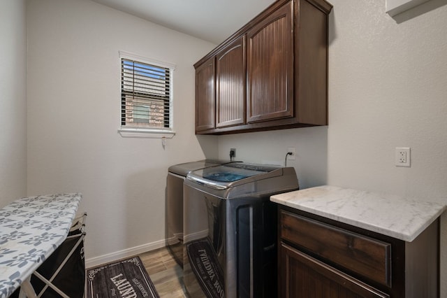 laundry room featuring separate washer and dryer, light wood-type flooring, cabinet space, and baseboards