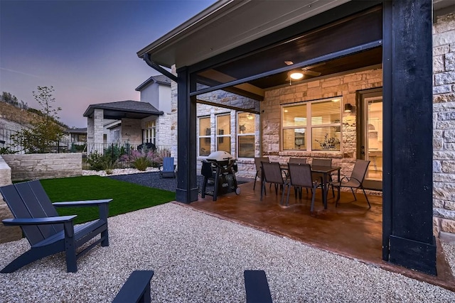219 Baldovino Skwy, Lakeway, TX 78738 - back of house at dusk with stone siding, a patio, and outdoor dining space