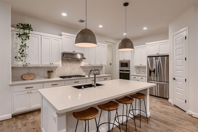 219 Baldovino Skwy, Lakeway, TX 78738 - kitchen with appliances with stainless steel finishes, tasteful backsplash, white cabinets, an island with sink, and recessed lighting