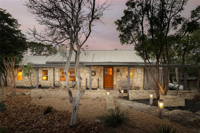 19745 Lakehurst Loop, Spicewood, TX 78669 - view of front facade featuring stone siding, a chimney, a porch, a metal roof, and a standing seam roof