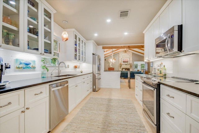 1920 River Rd, Wimberley, TX 78676 - kitchen featuring appliances with stainless steel finishes, a sink, decorative light fixtures, white cabinetry, and dark countertops