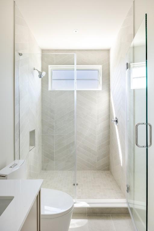 bathroom with toilet, a shower stall, a wealth of natural light, and tile patterned floors