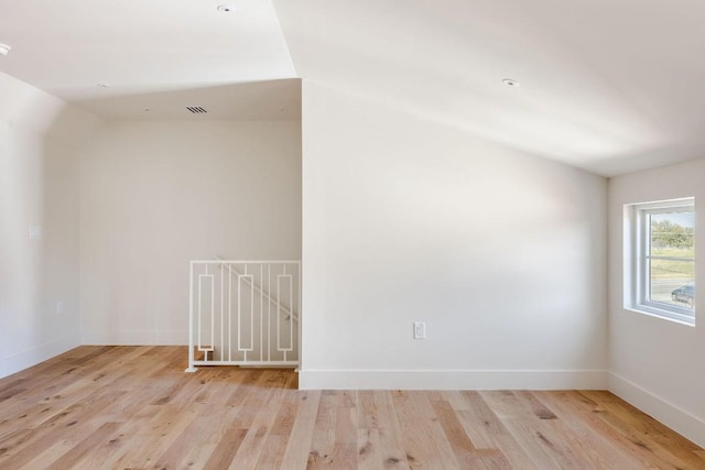 additional living space featuring light wood-type flooring, visible vents, and baseboards