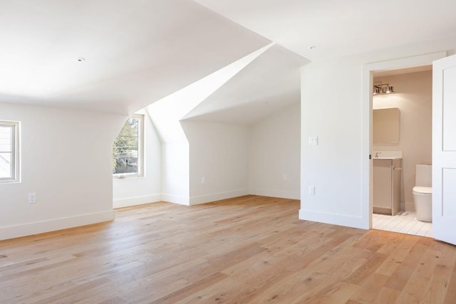 bonus room featuring light wood finished floors, baseboards, and vaulted ceiling