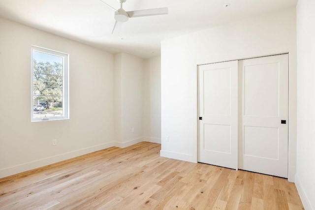 unfurnished bedroom featuring light wood-style floors, ceiling fan, baseboards, and a closet