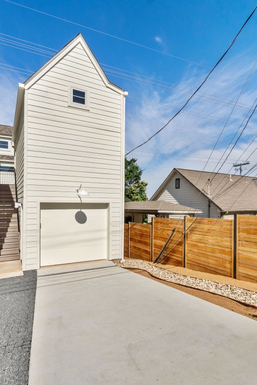 view of side of property with a garage, driveway, and fence