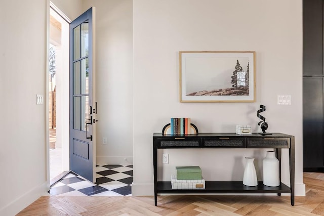 foyer entrance with light floors and baseboards