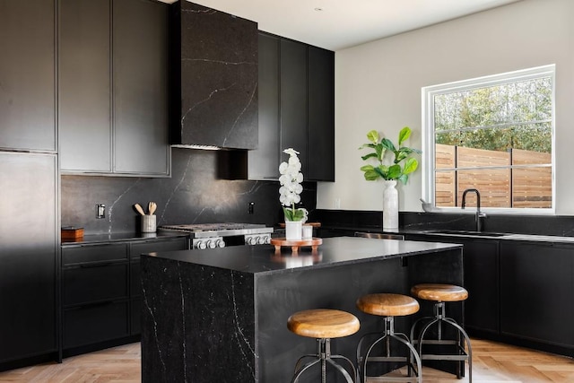 kitchen with a breakfast bar area, dark cabinets, stove, a sink, and a center island