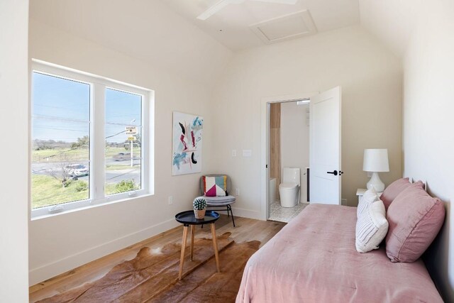 bedroom featuring attic access, vaulted ceiling, baseboards, and wood finished floors