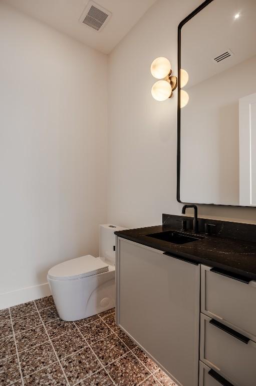 bathroom with visible vents, toilet, vanity, and baseboards