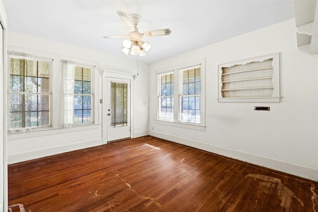 spare room with dark wood-style floors, ceiling fan, and baseboards