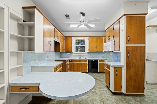 kitchen featuring white microwave, black dishwasher, light countertops, and a sink