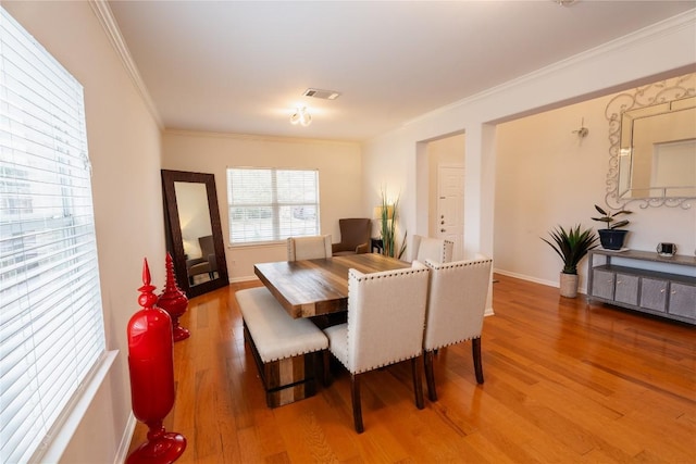 dining room featuring baseboards, wood finished floors, visible vents, and crown molding