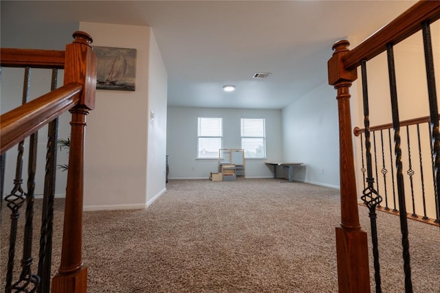 carpeted spare room with stairway, visible vents, and baseboards