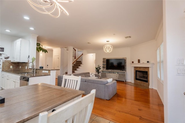 dining space with visible vents, a tiled fireplace, stairway, light wood-style floors, and a notable chandelier