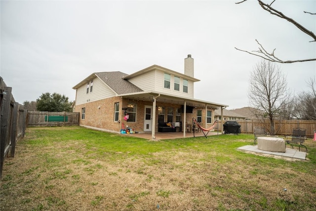 back of house featuring brick siding, a fenced backyard, a chimney, and a patio