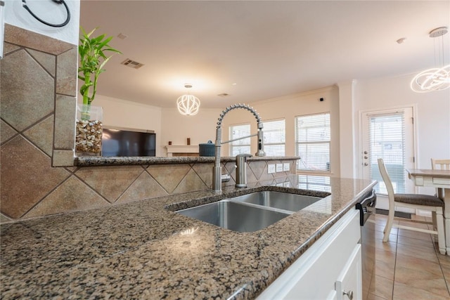 kitchen featuring ornamental molding, decorative light fixtures, a sink, and light tile patterned flooring