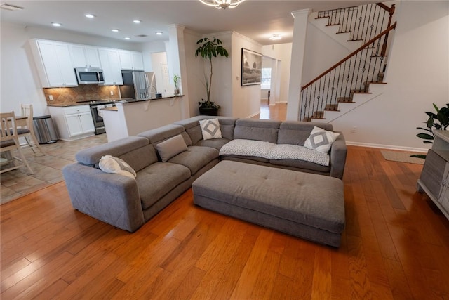 living room featuring light wood-style flooring, recessed lighting, visible vents, baseboards, and stairway