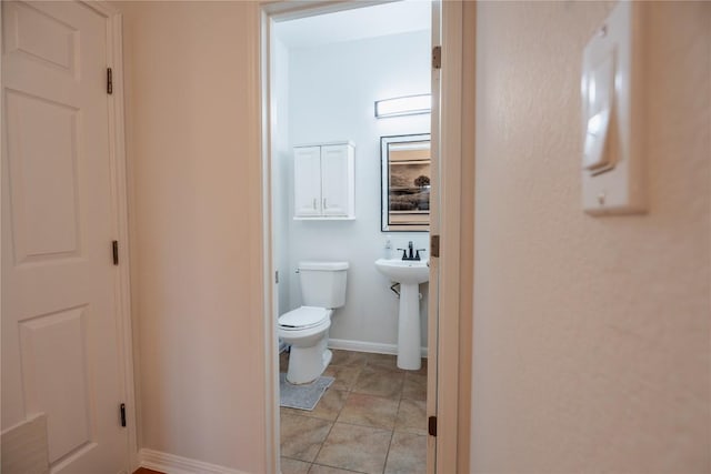 bathroom featuring a sink, tile patterned floors, toilet, and baseboards