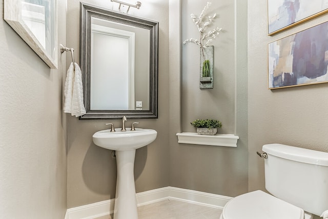 half bath featuring toilet and baseboards