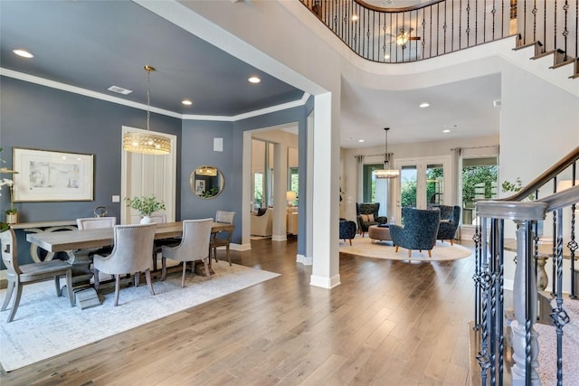 dining space featuring stairs, crown molding, wood finished floors, and a notable chandelier