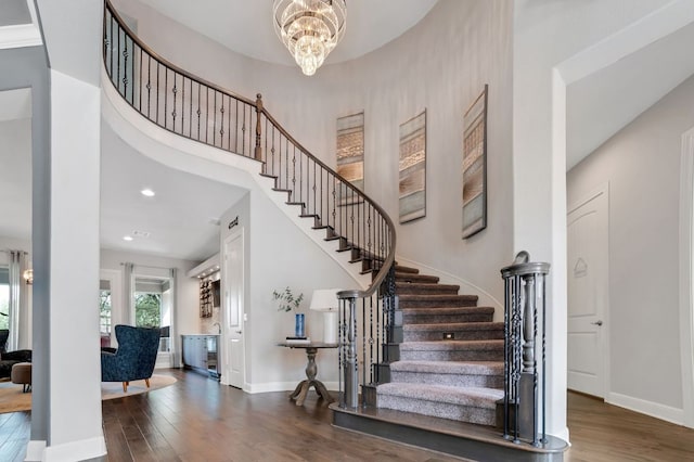 stairs with a notable chandelier, recessed lighting, wood finished floors, and baseboards