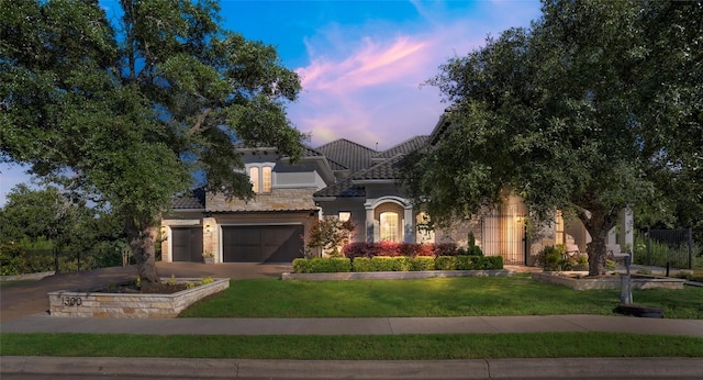 mediterranean / spanish house with an attached garage, a tile roof, stone siding, driveway, and stucco siding