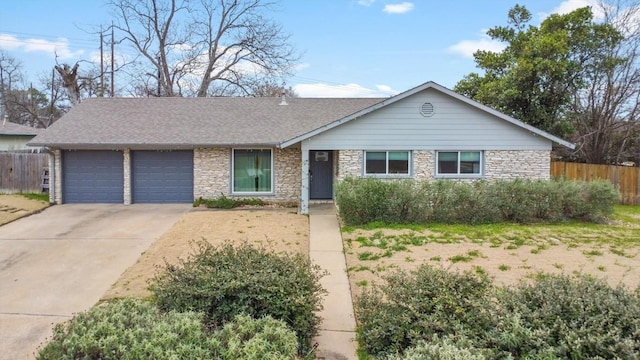 single story home with a garage, concrete driveway, fence, and stone siding