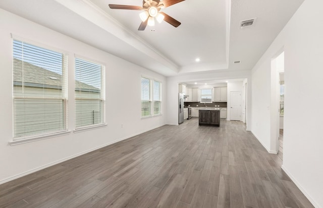 113 Crossbar St, Georgetown, TX 78633 - unfurnished living room featuring a ceiling fan, wood finished floors, a raised ceiling, baseboards, and recessed lighting