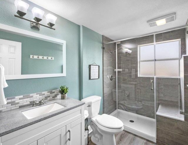 911 Sandy Mountain Dr, Sunrise Beach, TX 78643 - bathroom with a stall shower, decorative backsplash, toilet, wood finished floors, and a textured ceiling