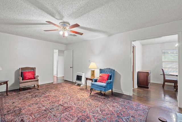 living area featuring dark wood-style floors, baseboards, a textured ceiling, and heating unit