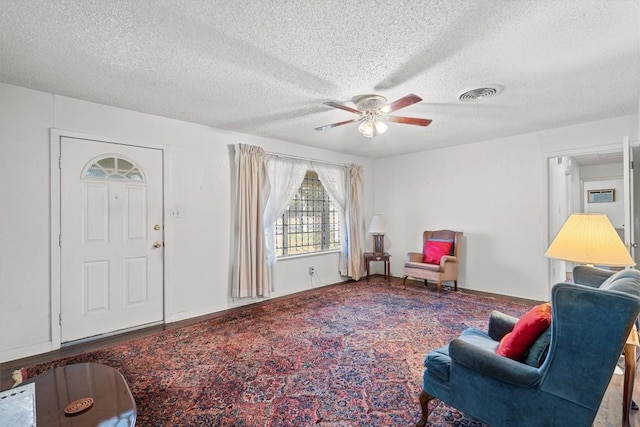 sitting room featuring baseboards, ceiling fan, visible vents, and a textured ceiling