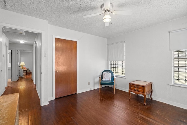 living area featuring dark wood-style flooring, ceiling fan, a textured ceiling, and baseboards