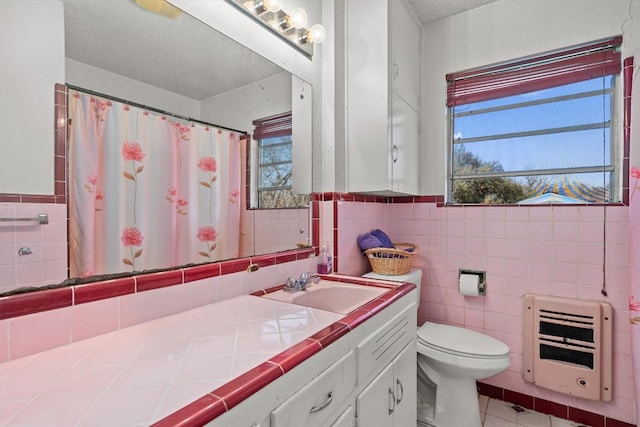 bathroom with a wealth of natural light, toilet, a textured ceiling, and heating unit