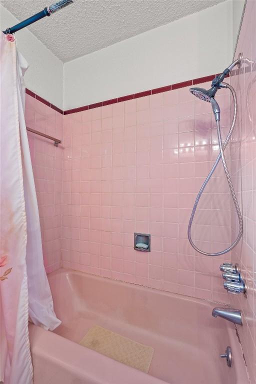 full bath with a textured ceiling and shower / tub combo with curtain