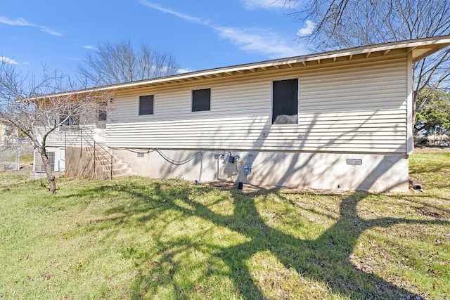 view of home's exterior with crawl space, a yard, and stairway