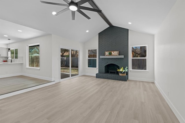 10505 Parkfield Dr, Austin, TX 78758 - unfurnished living room with a sink, baseboards, a fireplace, light wood-style flooring, and ceiling fan