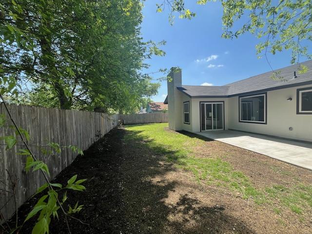10505 Parkfield Dr, Austin, TX 78758 - exterior space with stucco siding, a fenced backyard, a chimney, and a patio