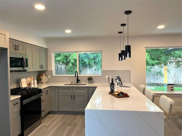 10505 Parkfield Dr, Austin, TX 78758 - kitchen featuring range with gas stovetop, a sink, stainless steel microwave, a peninsula, and gray cabinetry