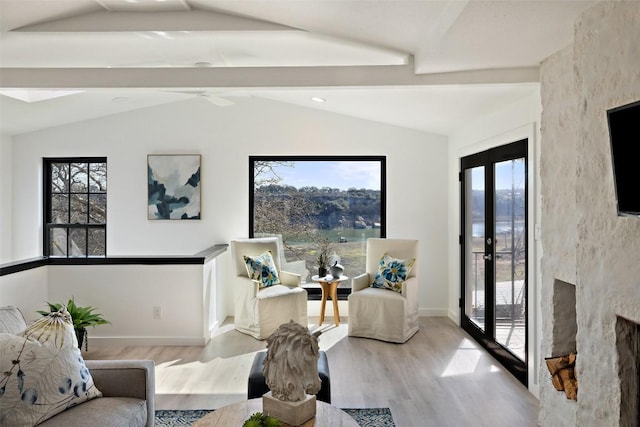 living room featuring baseboards, a healthy amount of sunlight, lofted ceiling with beams, and light wood finished floors