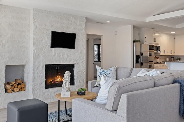 living area featuring light wood finished floors, a fireplace, beam ceiling, and recessed lighting