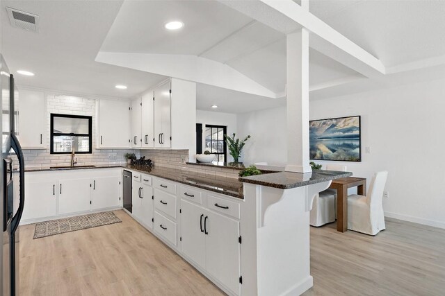 1201 Lake Shore Dr, Spicewood, TX 78669 - kitchen with light wood-type flooring, a peninsula, stainless steel dishwasher, tasteful backsplash, and white cabinets