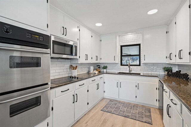 1201 Lake Shore Dr, Spicewood, TX 78669 - kitchen with appliances with stainless steel finishes, dark stone counters, backsplash, light wood-type flooring, and recessed lighting