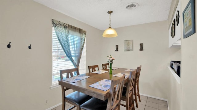 dining room featuring light tile patterned floors, a textured ceiling, visible vents, and baseboards