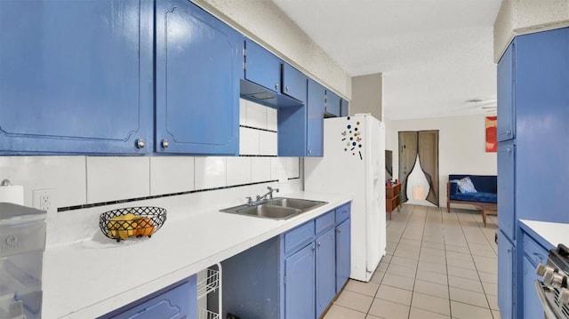 kitchen with stainless steel stove, blue cabinets, a sink, light countertops, and decorative backsplash