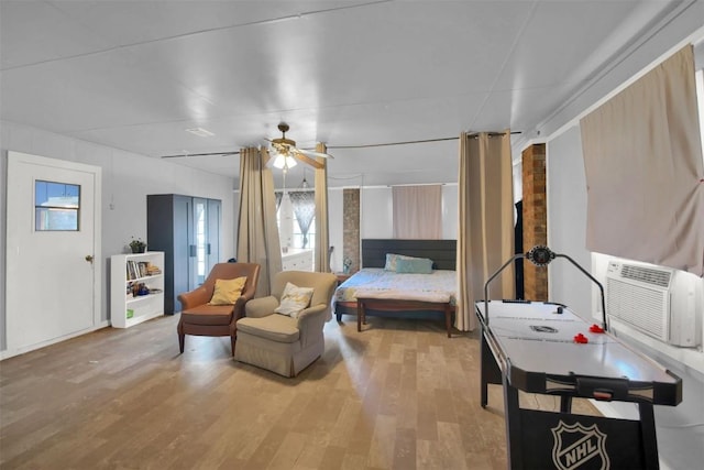 bedroom with ceiling fan, wood finished floors, and a wall mounted AC