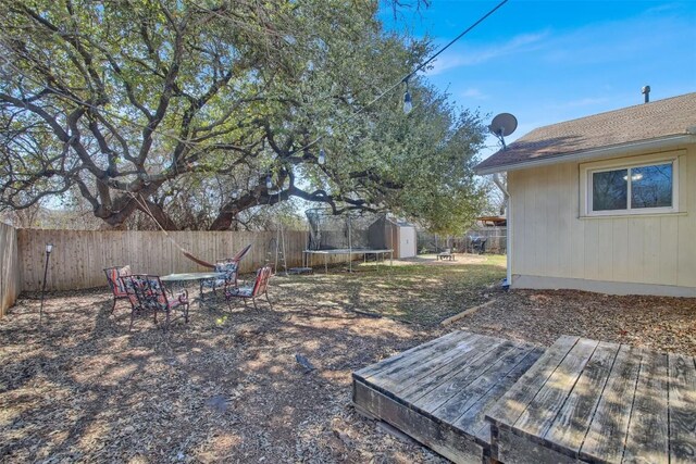 view of yard with a storage shed, a trampoline, an outbuilding, and a fenced backyard