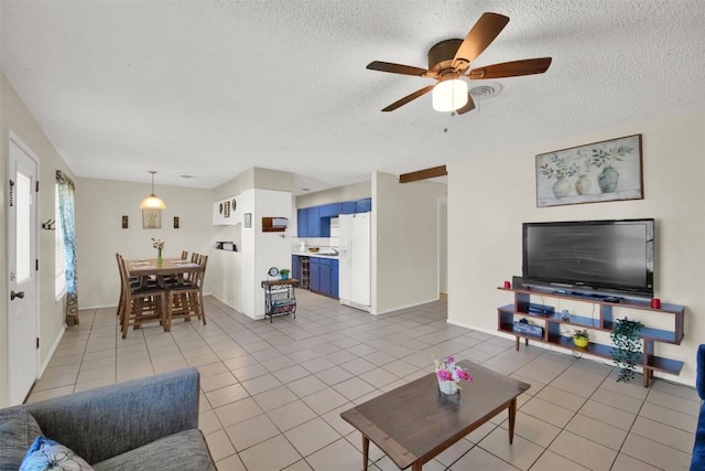 living room featuring a textured ceiling, baseboards, a ceiling fan, and tile patterned floors